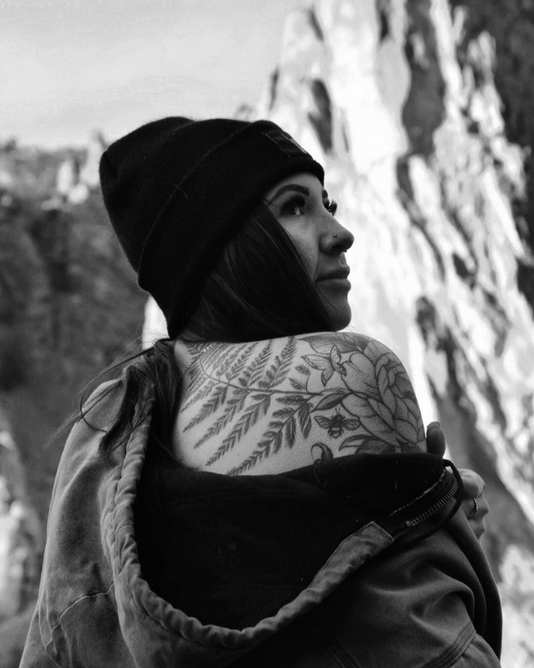 Maddy in a beanie showing her fern and floral shoulder tattoos