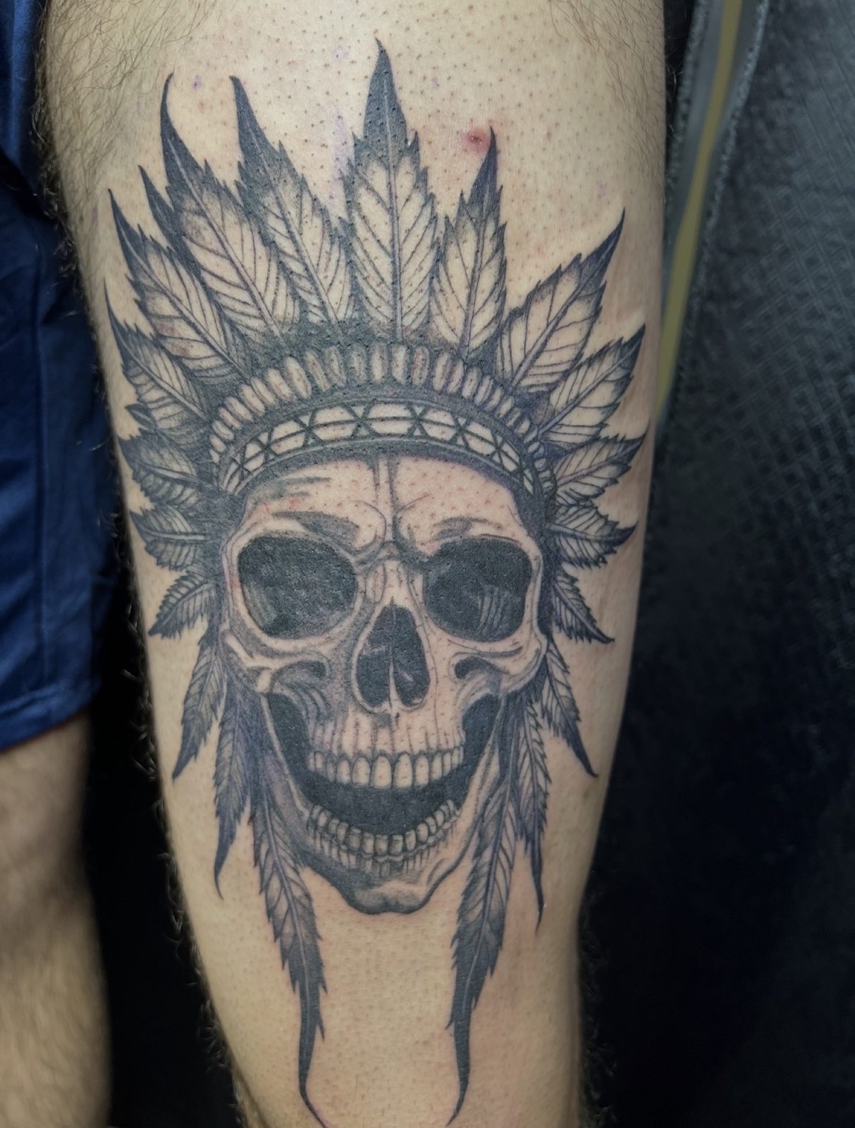 Illustrative skull wearing a leaf headdress, tattooed on the thigh
