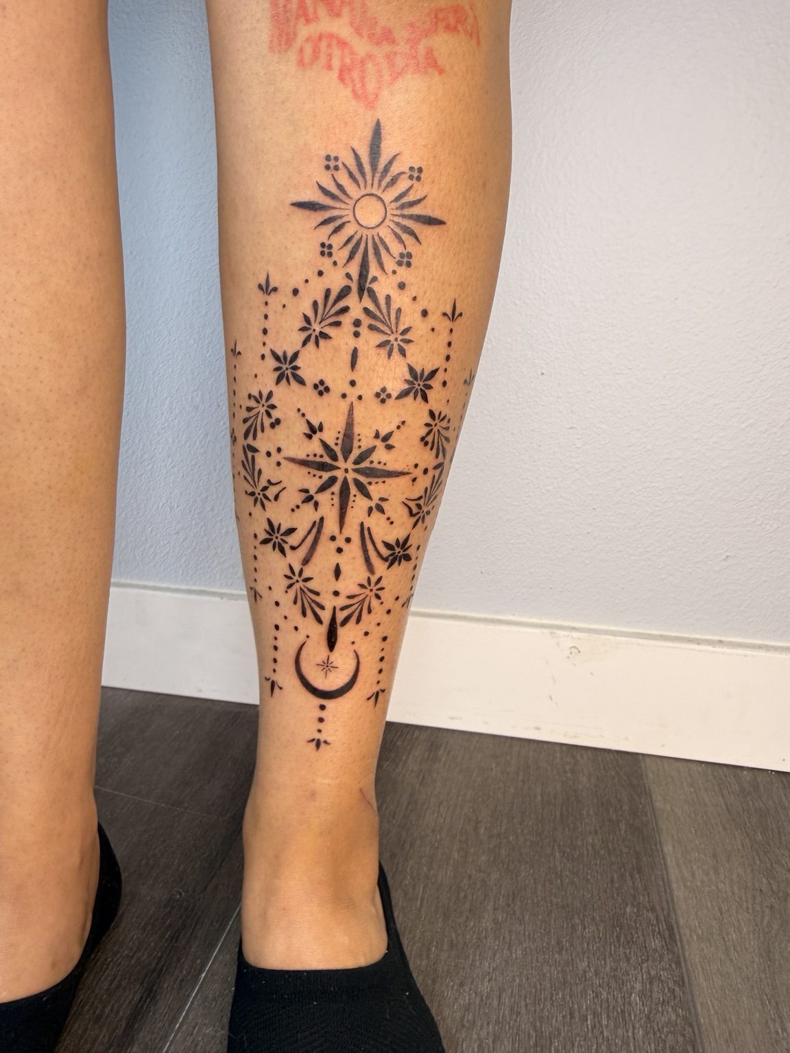 Ornamental leg tattoo with stars and a crescent moon