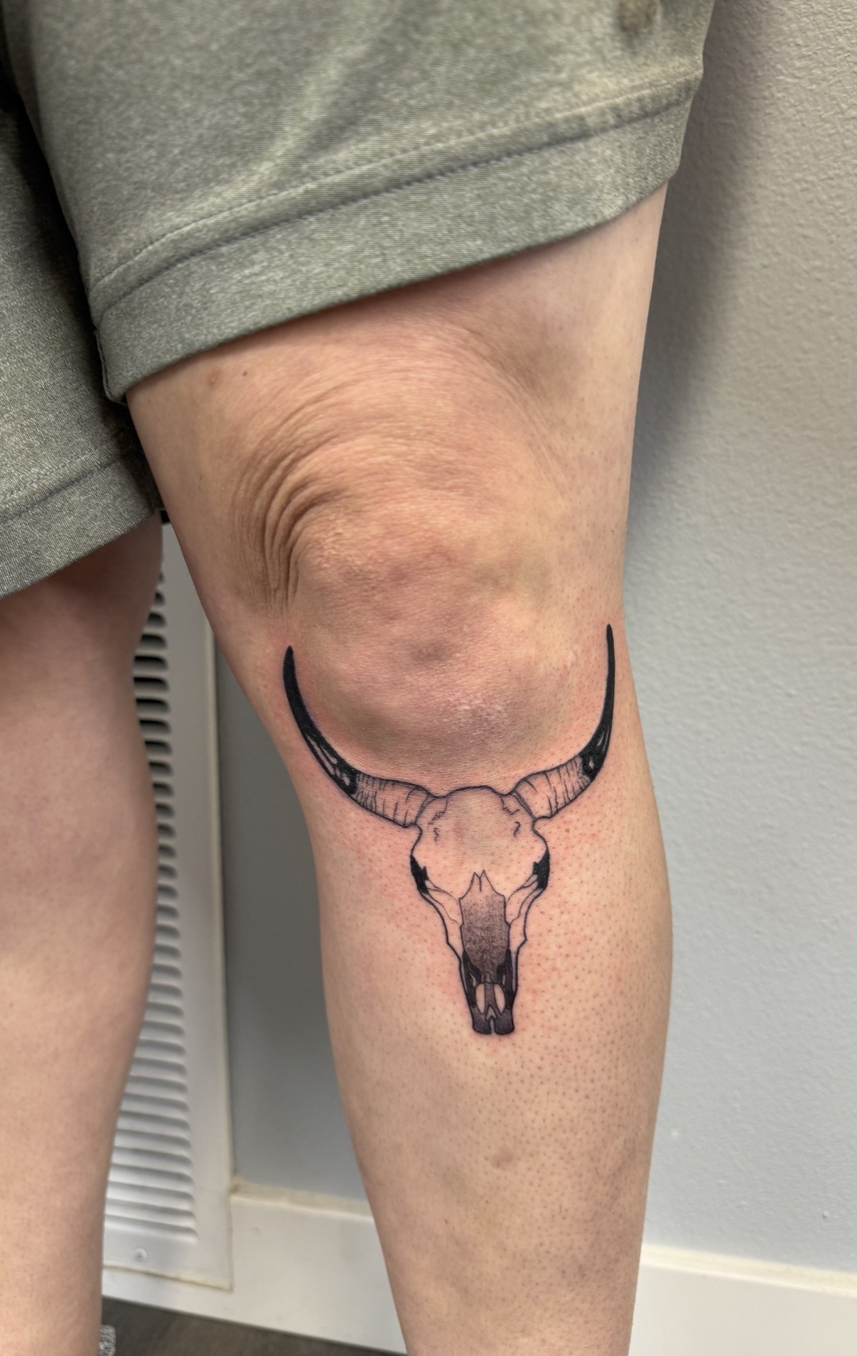 Fine line longhorn skull tattoo on the knee